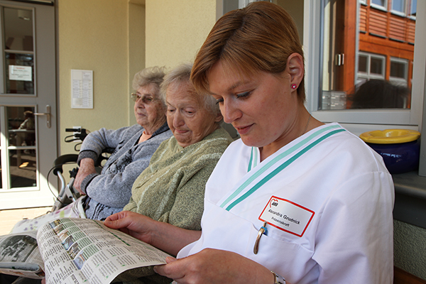 Senioren mit Betreuerin bei der Zeitungsschau